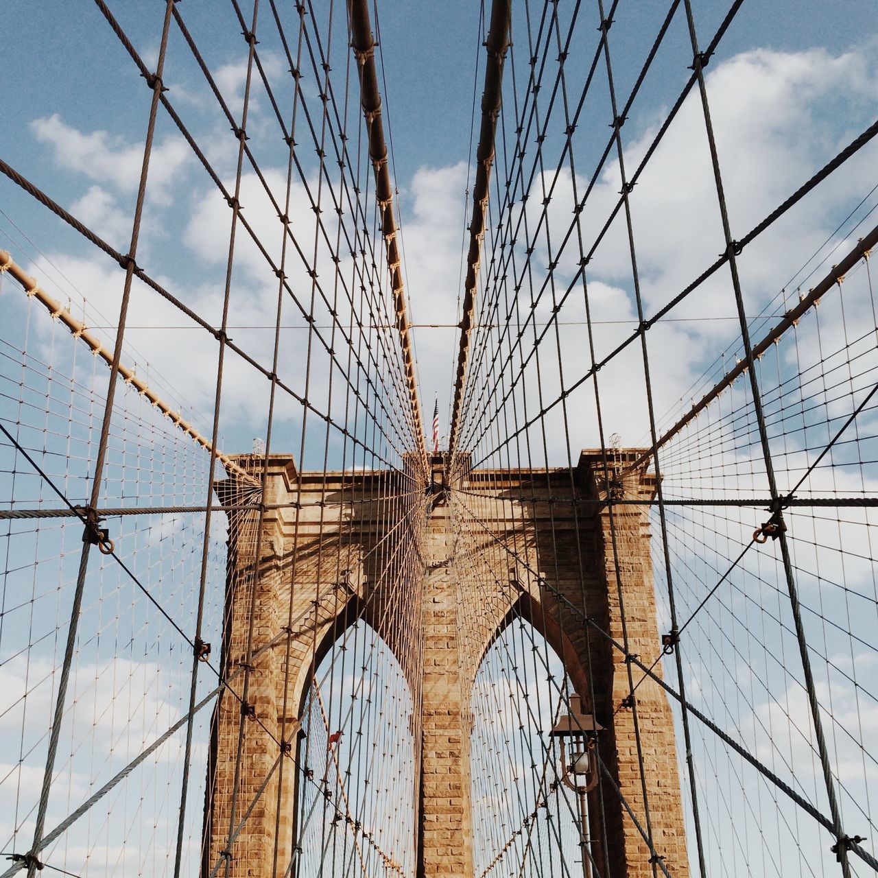 low angle view, architecture, built structure, connection, sky, suspension bridge, bridge - man made structure, engineering, cable, international landmark, cloud - sky, famous place, steel cable, travel destinations, cloud, cable-stayed bridge, power line, bridge, electricity pylon, brooklyn bridge