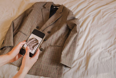 Midsection of woman using mobile phone on bed
