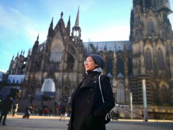 Woman standing outside cologne cathedral on street in city
