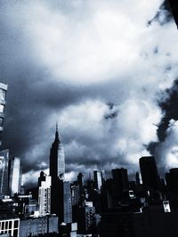 Low angle view of skyscrapers against cloudy sky