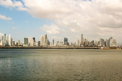 Sea by buildings against sky in city