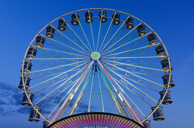 Low angle view of ferris wheel against blue sky