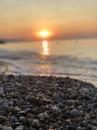 Stones on beach against sky during sunset