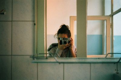 Woman taking selfie through camera reflecting on mirror at home