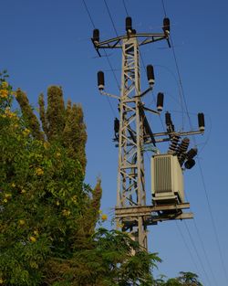 Low angle view of electricity pylon against clear blue sky