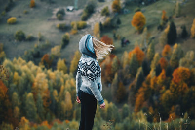 Woman in sweater standing against trees