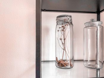 Close-up of glass jar on table against wall