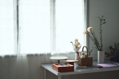 Flower vase on table by window at home