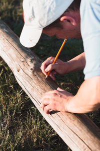 Man measuring wood and marking at field 