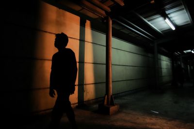 Silhouette man walking in illuminated tunnel