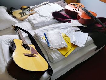 High angle view of papers with string instruments on bed