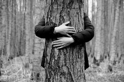 Man embracing tree trunk in forest