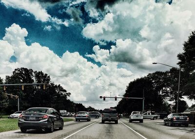 Cars on road against cloudy sky