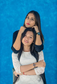 Portrait of beautiful women standing against blue wall