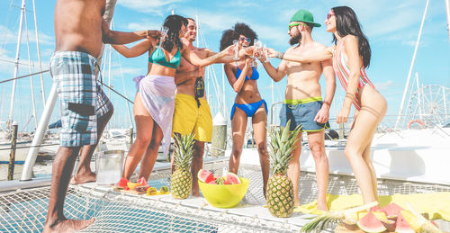 Smiling friends raising toast while standing in ship