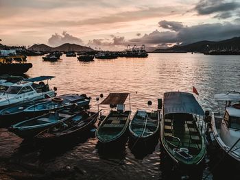 Boats moored in sea against sky during sunset