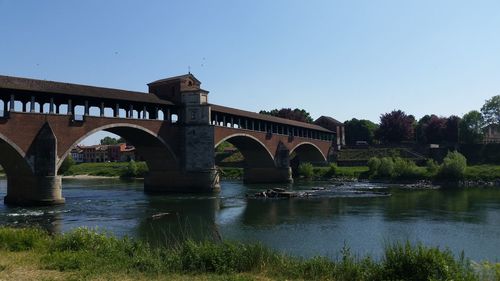 Arch bridge over river against clear sky