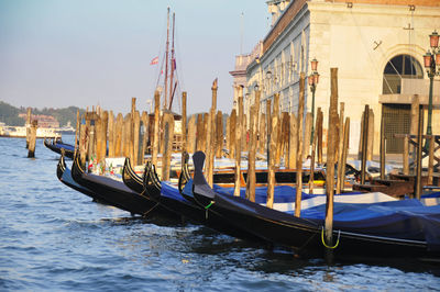 Gondola boats moored in lake against sky