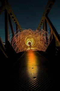 Illuminated wirewools on footbridge against sky at night