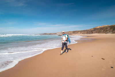 Rear view of woman walking at beach against sky