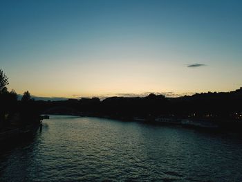 Scenic view of river against clear sky at sunset