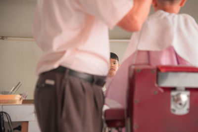 Midsection of barber cutting boy hair at salon