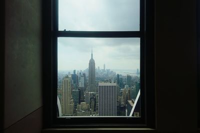 Modern buildings against sky seen through glass window