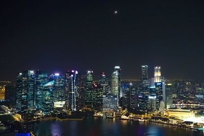 Illuminated buildings in city against sky at night