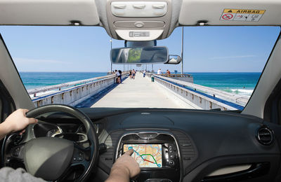 Cropped hand of man driving car on pier