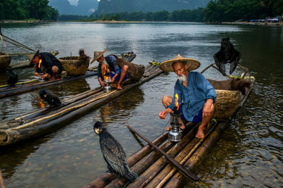 Men with birds on wooden rafts in lake