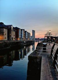 Canal amidst buildings in city against sky during sunset