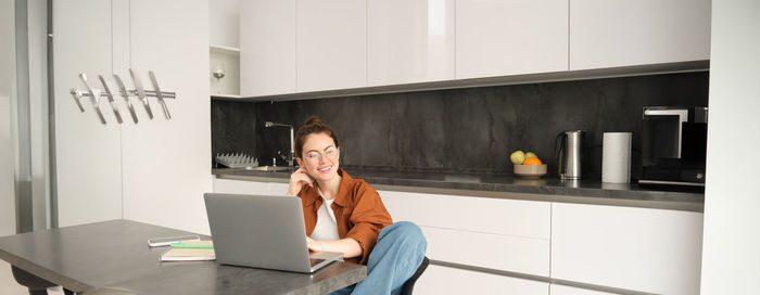 Side view of woman using mobile phone while sitting at home