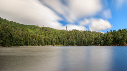 Lake with trees against cloudy sky