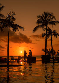 Silhouette people at beach against sky during sunset