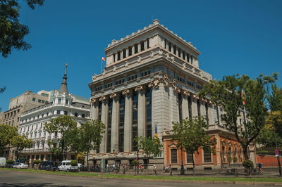 Old buildings on the busy alcala street with people and cars, in a sunny day at madrid, spain.