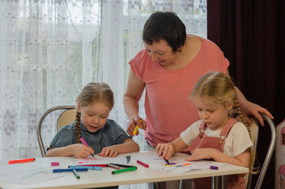 Grandmother sitting with granddaughters during painting