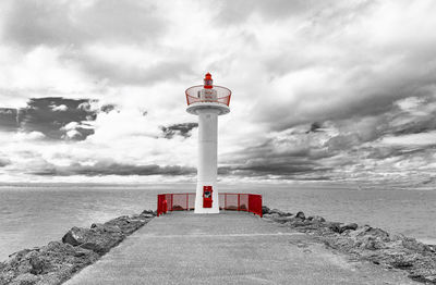 Lighthouse by sea against sky