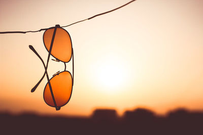 Close-up of sunglasses hanging on string during sunset