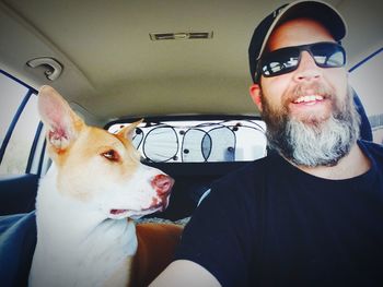 Portrait of man with dog in car