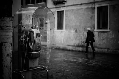 Full length of man by phone booth in city