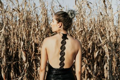 Rear view of woman standing against plants on agricultural field