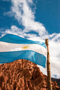 Low angle view of flag on mountain against sky