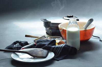 Steaming waffle iron with bowl of batter, bottle of milk, cinnamon sticks and cooking utensils