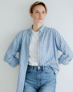 Portrait of young woman standing against white background