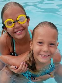 Portrait of smiling siblings swimming in pool