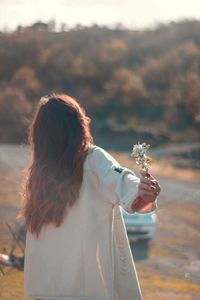 Rear view of woman with umbrella standing on rock