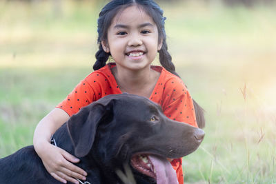 Portrait of smiling woman with dog on field