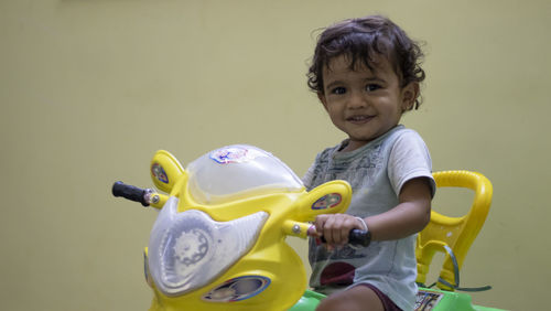 A little kid playing his car with a toy and feeling happy, at inside home