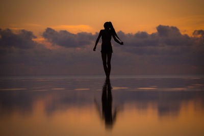 Silhouette man standing on beach against sky during sunset