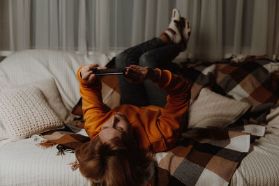 Pretty woman resting on couch, using applications on smartphone. femaly chatting 